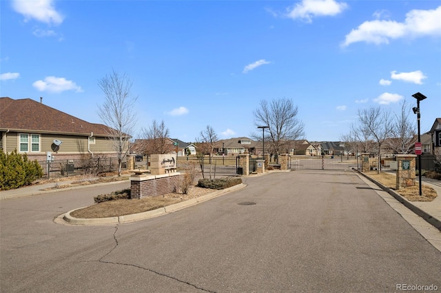 view of street with a gate, curbs, and a residential view