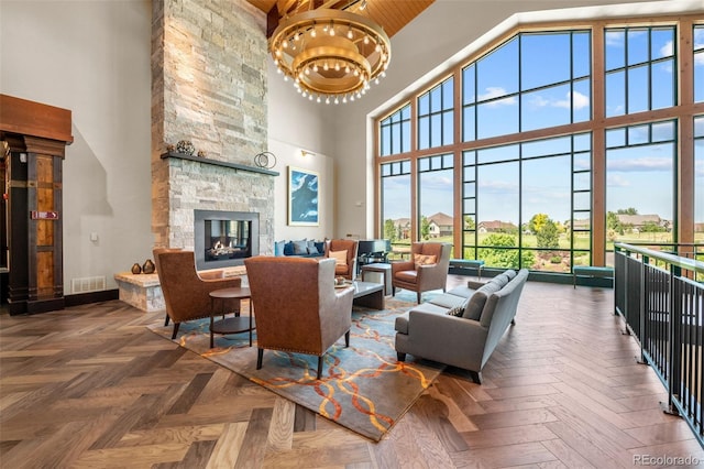 living area with visible vents, a notable chandelier, a high ceiling, and a fireplace