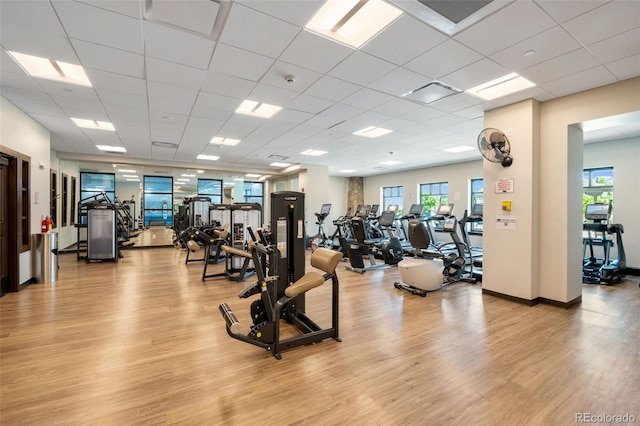 gym with light wood finished floors, a drop ceiling, baseboards, and visible vents