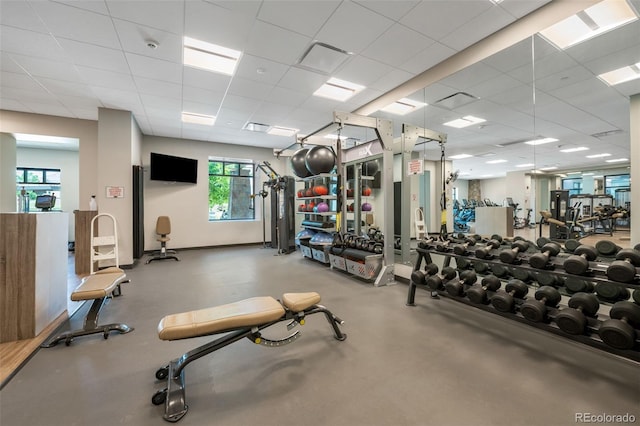 gym featuring a drop ceiling and baseboards