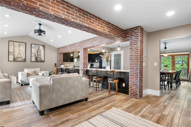 living room featuring light wood-style flooring, baseboards, recessed lighting, brick wall, and lofted ceiling