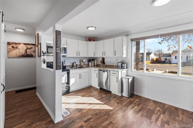 kitchen with dark wood-type flooring, appliances with stainless steel finishes, sink, and white cabinets