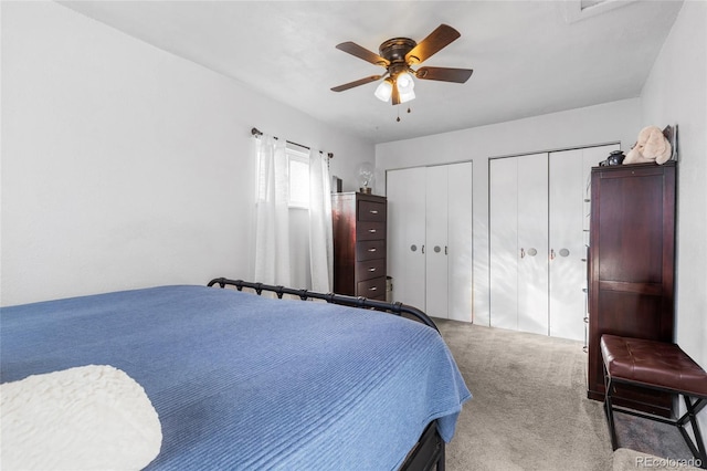 carpeted bedroom with two closets and ceiling fan