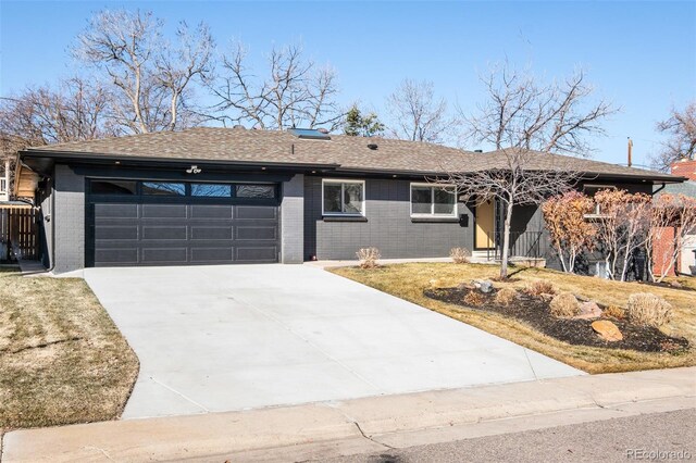 ranch-style house with concrete driveway, brick siding, an attached garage, and a shingled roof