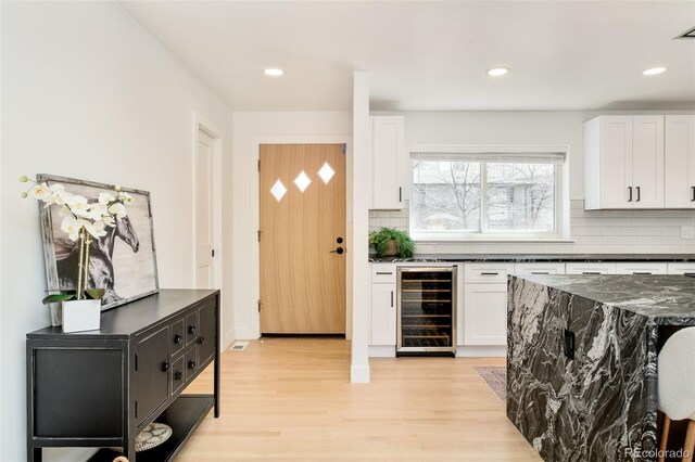 bar featuring beverage cooler, decorative backsplash, recessed lighting, and light wood-type flooring