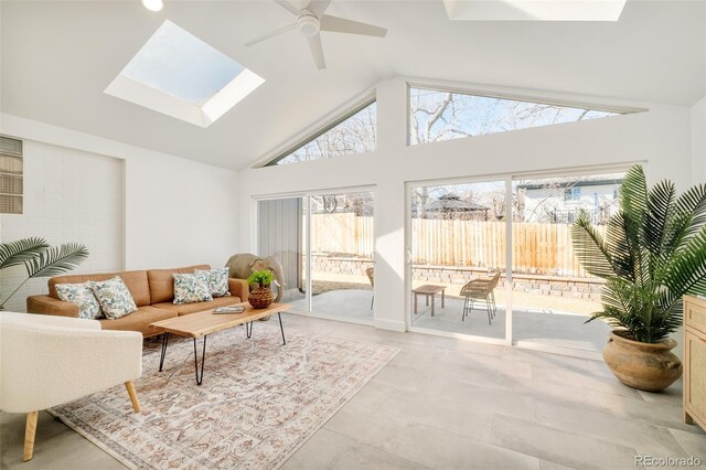 living area featuring a skylight, high vaulted ceiling, and ceiling fan