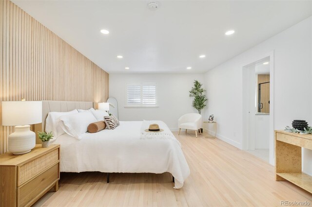bedroom with recessed lighting, baseboards, light wood-style flooring, and ensuite bath