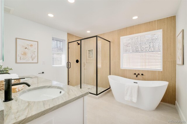 bathroom with recessed lighting, a sink, a freestanding tub, and a stall shower