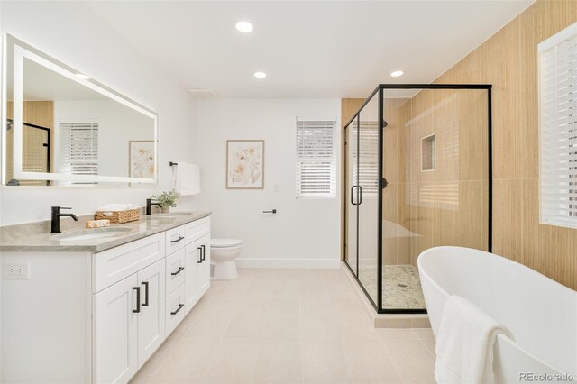 full bath with double vanity, a freestanding tub, a shower stall, and a sink