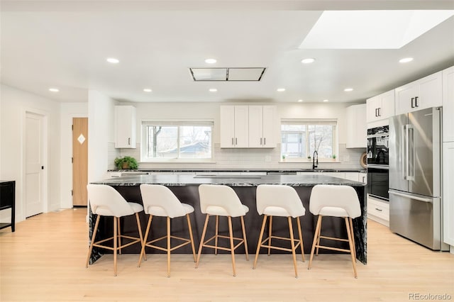 621 S Harrison Ln, Denver, CO 80209 - kitchen featuring high end refrigerator, a sink, light wood-type flooring, backsplash, and a center island