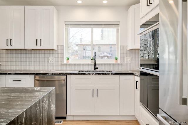 621 S Harrison Ln, Denver, CO 80209 - kitchen featuring appliances with stainless steel finishes, recessed lighting, white cabinetry, and dark stone countertops