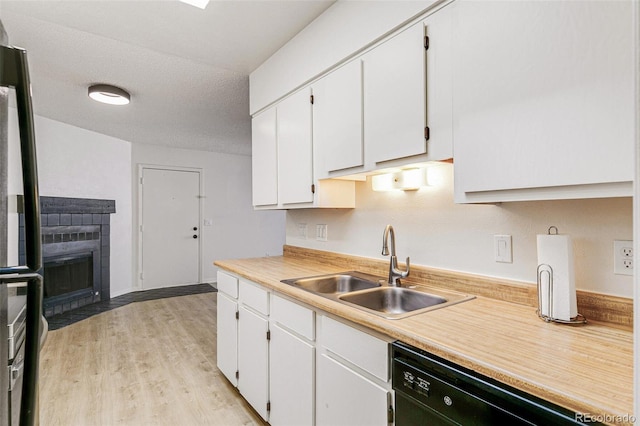 kitchen featuring black appliances, white cabinets, light countertops, and a sink