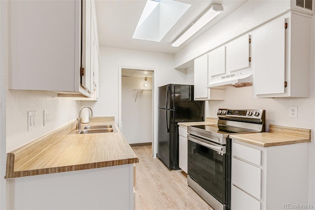 kitchen featuring under cabinet range hood, electric stove, freestanding refrigerator, white cabinets, and a sink