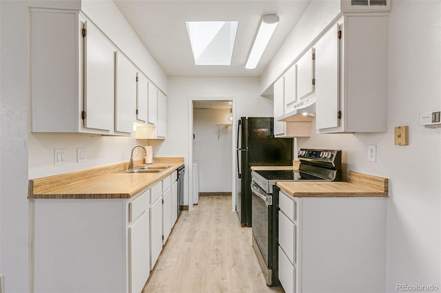 kitchen featuring light wood finished floors, under cabinet range hood, appliances with stainless steel finishes, white cabinets, and a sink