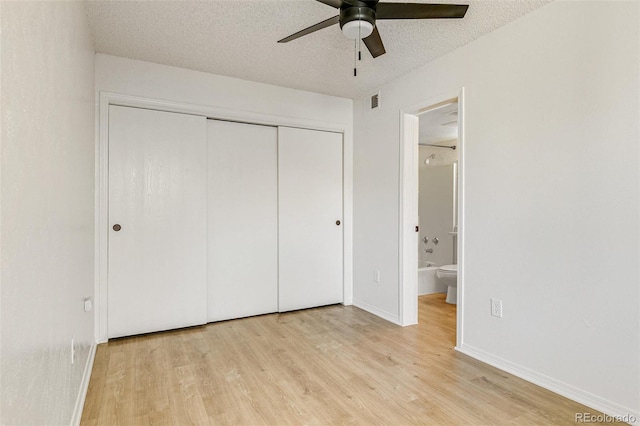 unfurnished bedroom featuring a closet, baseboards, a textured ceiling, and light wood-style flooring