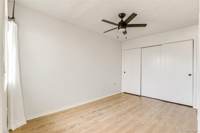 unfurnished bedroom featuring light wood finished floors, baseboards, a textured ceiling, and a closet