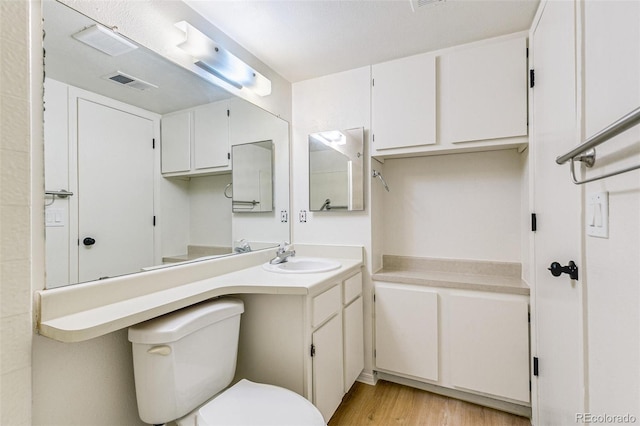 bathroom featuring visible vents, toilet, wood finished floors, and vanity