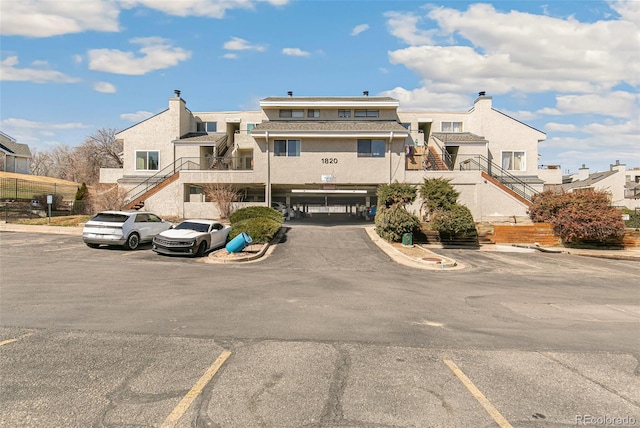 view of building exterior with stairs, uncovered parking, and a residential view