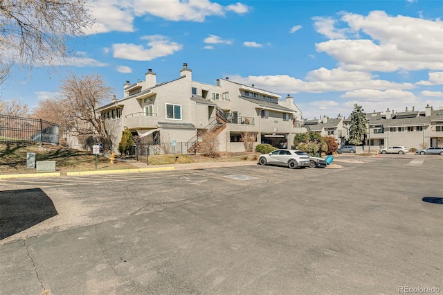 view of building exterior featuring fence, a residential view, and uncovered parking