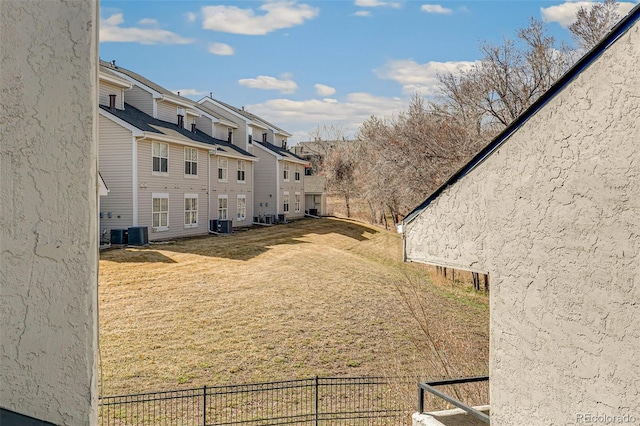 view of yard featuring a residential view, central air condition unit, and fence