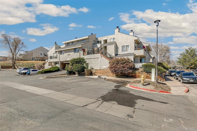 view of front of home with stucco siding, a residential view, a chimney, and stairway