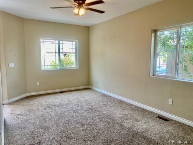 spare room featuring carpet floors, a wealth of natural light, and ceiling fan