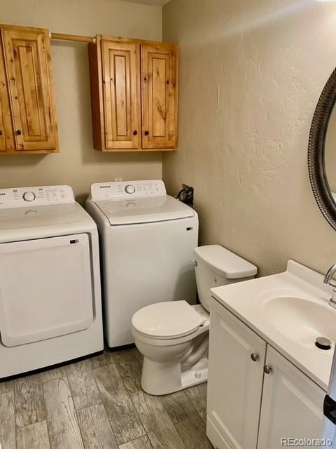 bathroom featuring hardwood / wood-style floors, vanity, toilet, and separate washer and dryer