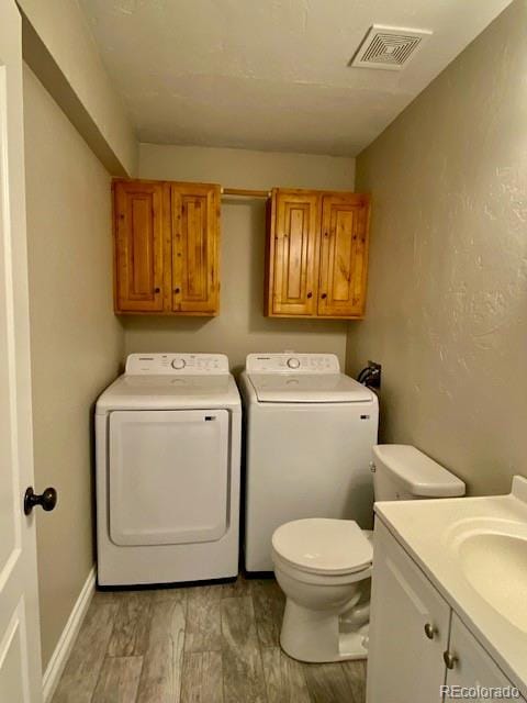 laundry room featuring washing machine and dryer, sink, and light hardwood / wood-style flooring