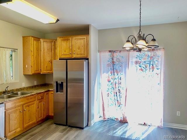 kitchen with sink, an inviting chandelier, decorative light fixtures, appliances with stainless steel finishes, and light wood-type flooring