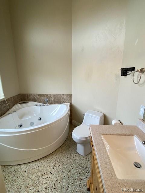 bathroom featuring a bathing tub, vanity, and toilet