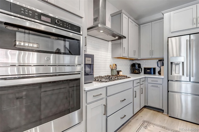8049 Monte Vista Cir, Littleton, CO 80125 - kitchen featuring stainless steel appliances, wall chimney exhaust hood, gray cabinetry, light countertops, and light wood-type flooring