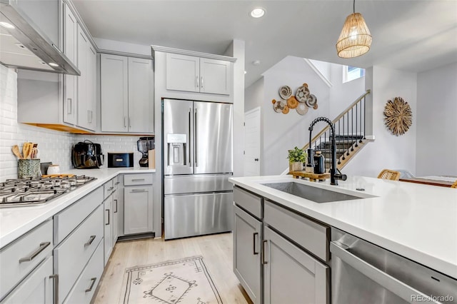 8049 Monte Vista Cir, Littleton, CO 80125 - kitchen featuring appliances with stainless steel finishes, wall chimney range hood, gray cabinets, a sink, and recessed lighting