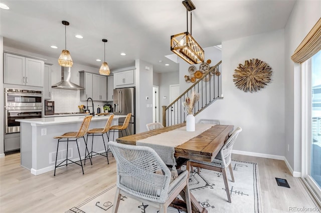 8049 Monte Vista Cir, Littleton, CO 80125 - dining space featuring light wood-type flooring, stairway, recessed lighting, baseboards, and a chandelier