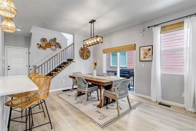 8049 Monte Vista Cir, Littleton, CO 80125 - dining room featuring stairway, light wood-type flooring, baseboards, and a chandelier