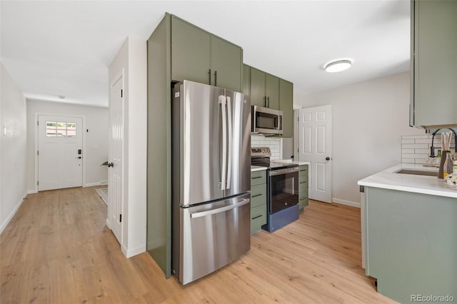 1205 W 101st Ave, Northglenn, CO 80260 - kitchen with stainless steel appliances, green cabinets, a sink, and decorative backsplash