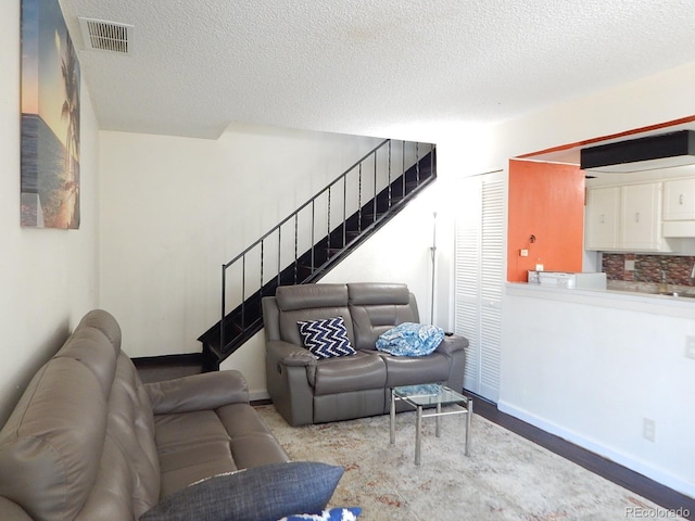 living area with visible vents, stairway, baseboards, and a textured ceiling