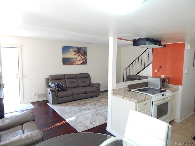 living room featuring baseboards, stairs, and visible vents