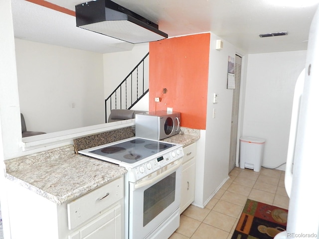 kitchen with light tile patterned floors, light countertops, visible vents, white cabinets, and white appliances