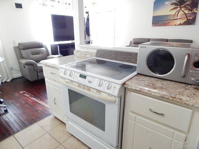 kitchen with electric range, white cabinetry, a wealth of natural light, and light tile patterned flooring