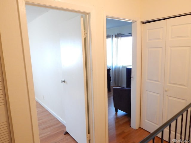 hall with light wood-style flooring and baseboards