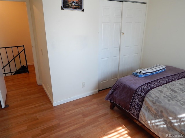 bedroom featuring light wood finished floors, baseboards, and a closet