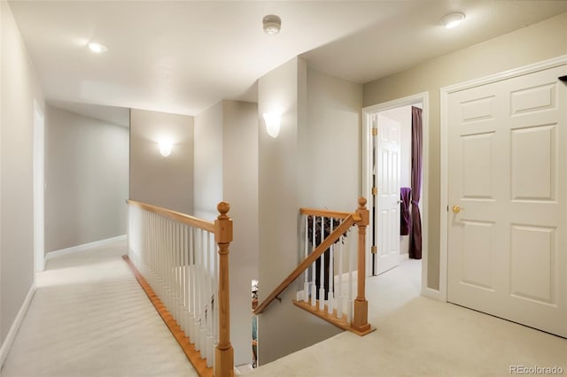 hall featuring an upstairs landing and baseboards