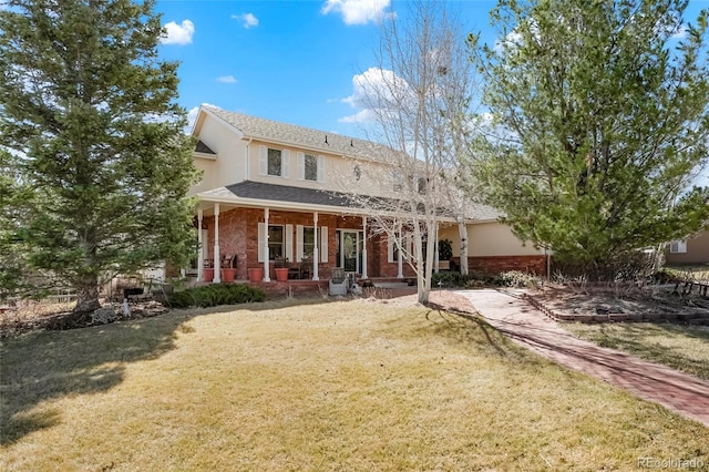 back of house with brick siding, a lawn, covered porch, and stucco siding