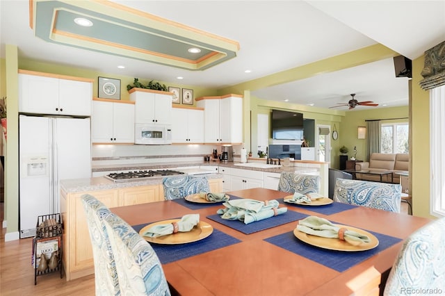 dining area featuring recessed lighting, a raised ceiling, light wood-style floors, and ceiling fan