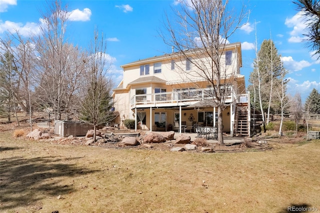 rear view of house with stucco siding, a lawn, a patio, a wooden deck, and stairs