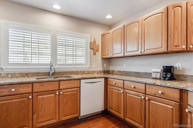 kitchen featuring visible vents, a sink, wood finished floors, light stone countertops, and dishwasher