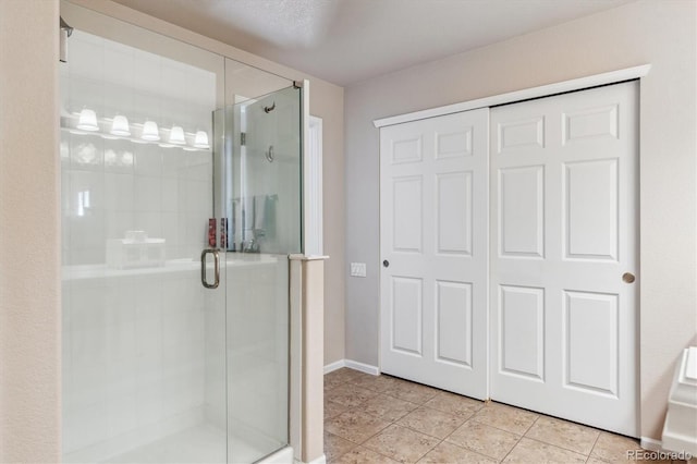 bathroom with tile patterned floors, baseboards, and a stall shower