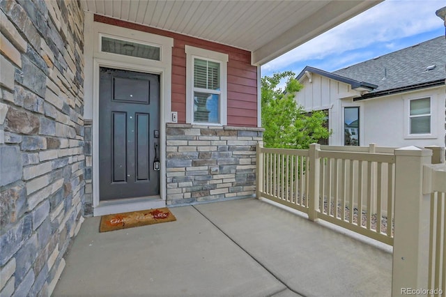 21900 E 46th Pl, Aurora, CO 80019 - doorway to property with stone siding, board and batten siding, and covered porch