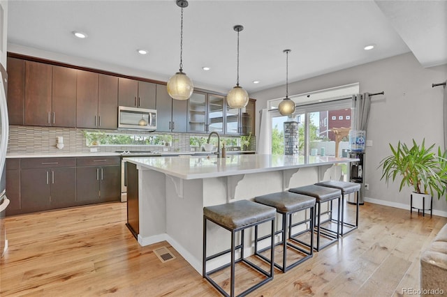 21900 E 46th Pl, Aurora, CO 80019 - kitchen featuring stove, stainless steel microwave, light countertops, a kitchen bar, and tasteful backsplash