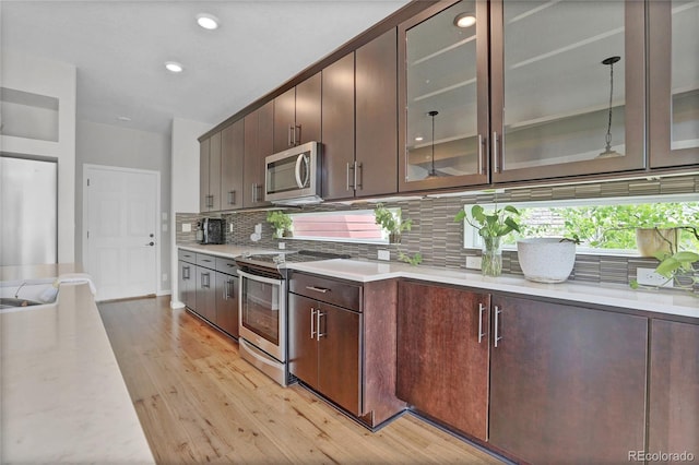 21900 E 46th Pl, Aurora, CO 80019 - kitchen featuring appliances with stainless steel finishes, light countertops, light wood-style flooring, backsplash, and dark brown cabinetry